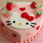 A cute Hello Kitty cake decorated with pink frosting, white icing, and a fondant Hello Kitty face on top.