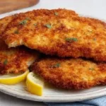 Golden crispy chicken cutlets served with lemon wedges and dipping sauce