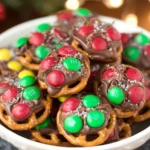 Rolo pretzels topped with melted chocolate caramel candies and colorful M&M chocolates on a baking sheet.
