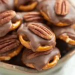 Pecan Rolo Pretzels topped with toasted pecans on a baking sheet